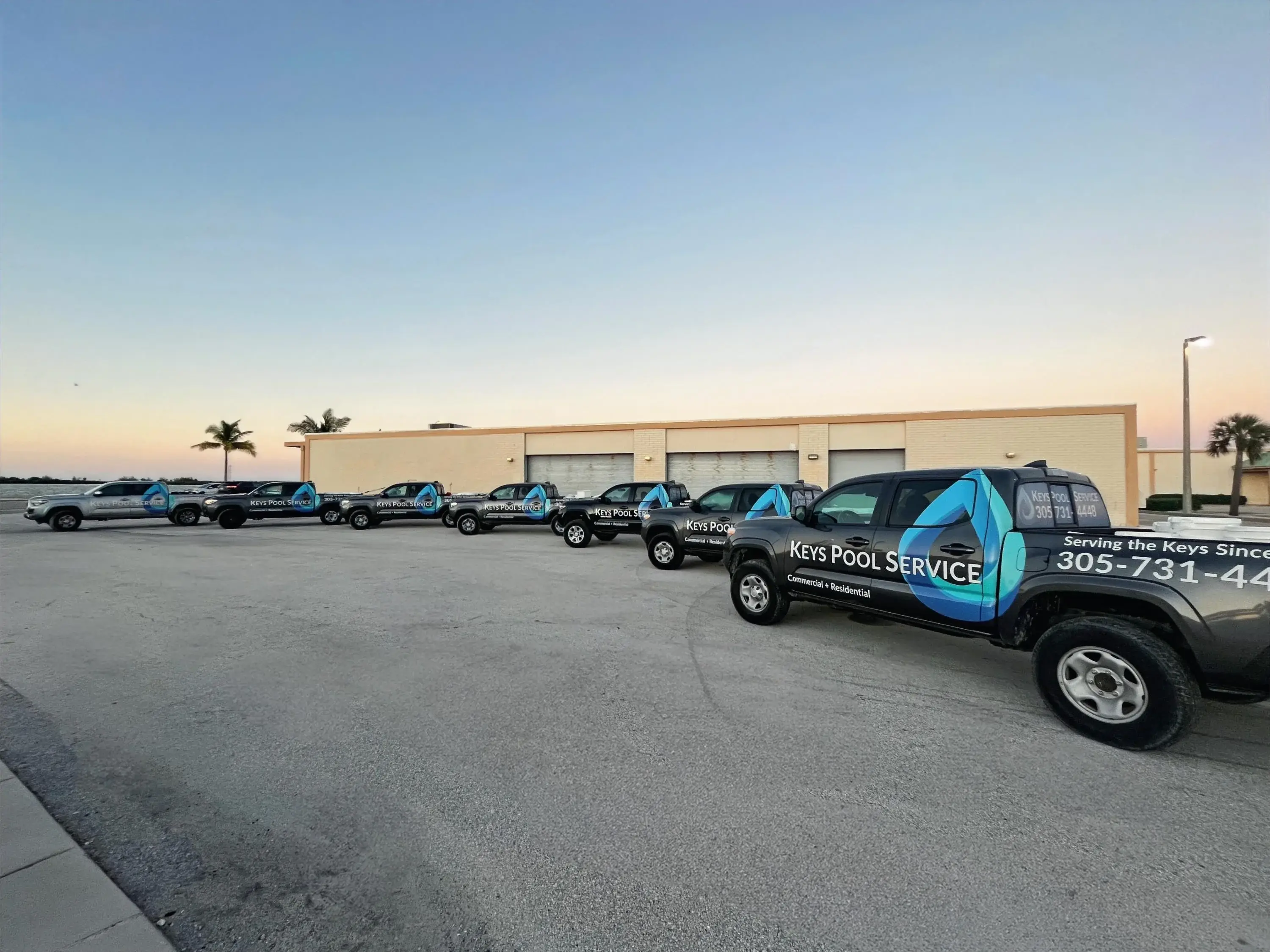 The Keys Pool Service fleet of service trucks lined up in Key West at sunset
